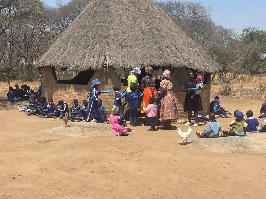 Kinder und Betreuerinnen bei der Schulspeisung in Simbabwe.