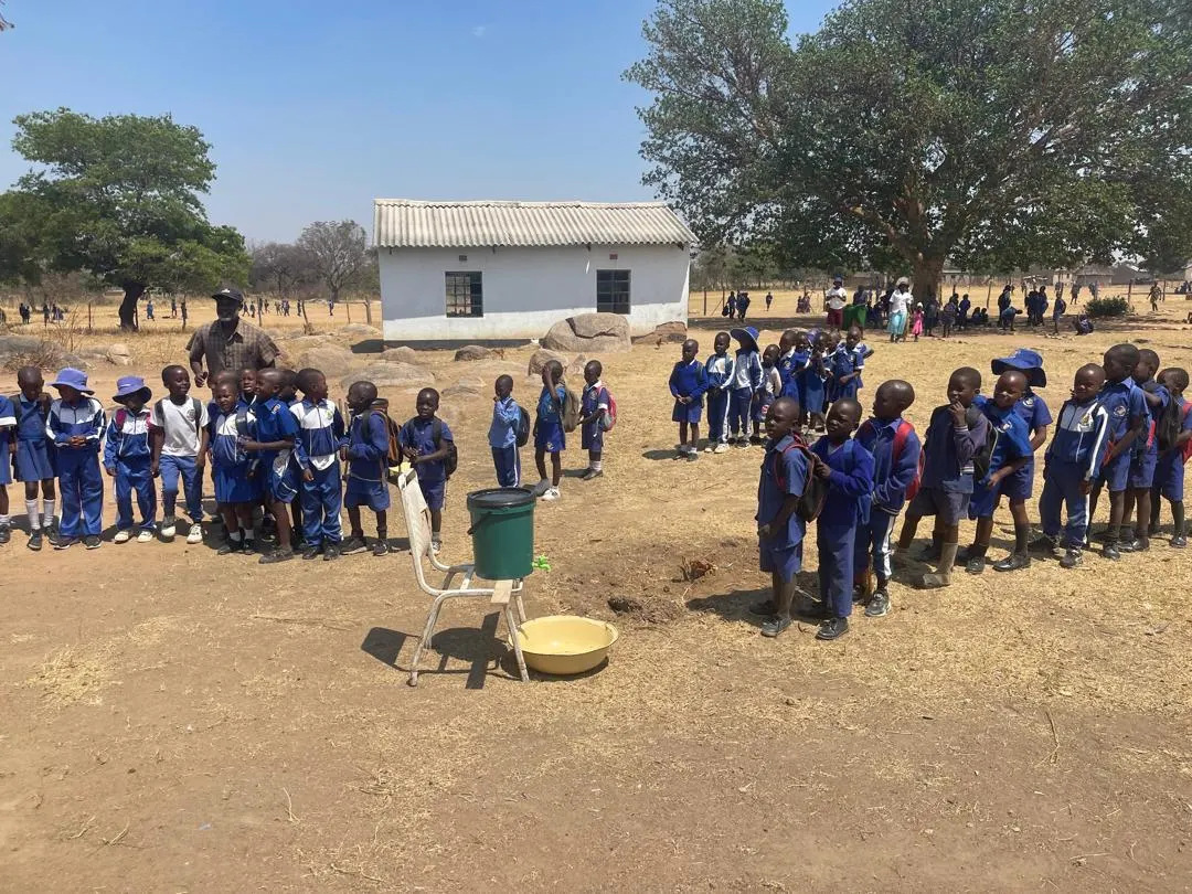 Schulkinder und Lehrkräfte auf einem Schulhof in Simbabwe.